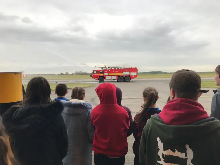 A group of young people watching a fire brigade vehicle